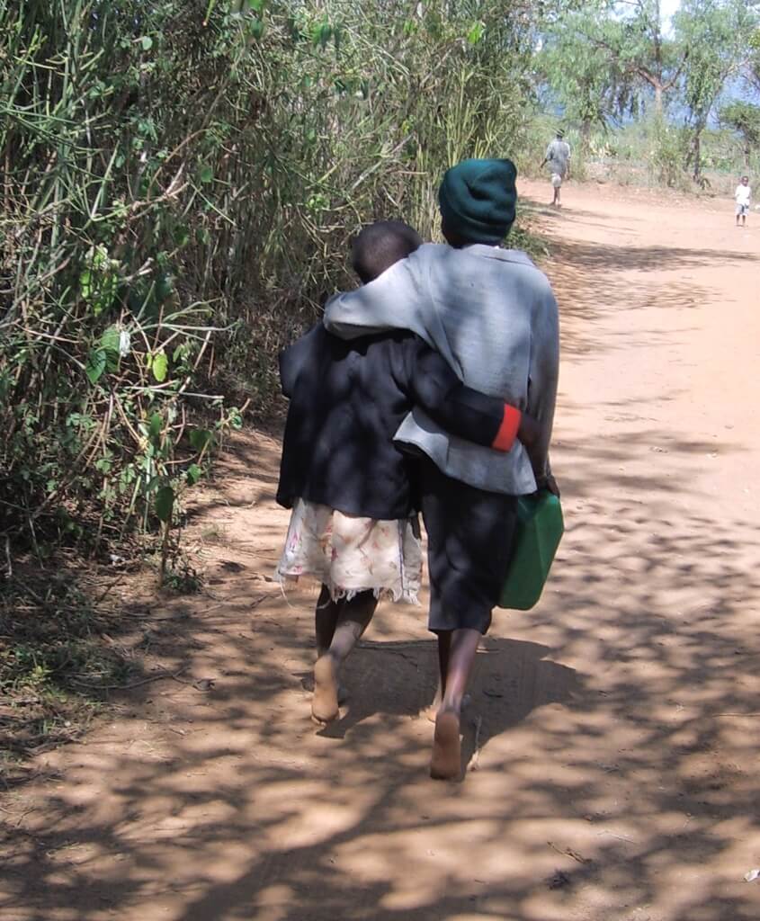Two Kenyan children walking arm in arm providing for needs