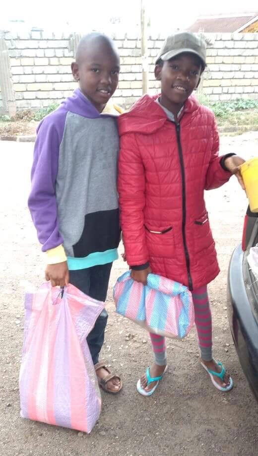 two young girls holding bags of food they received during the coronavirus lockdown