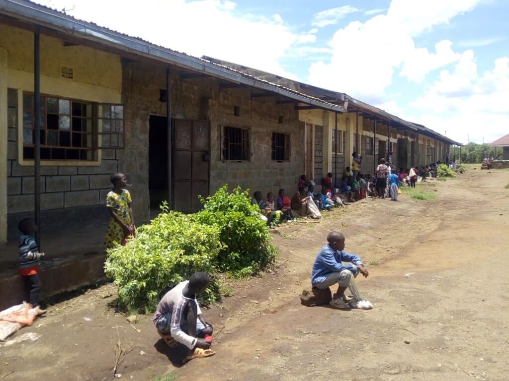 Kenyan students sitting six feet apart outside a school