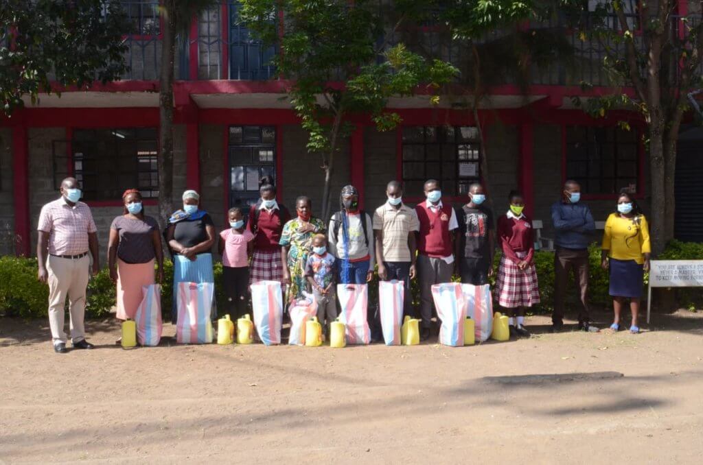 A group of 8 students at Bishop Donovan Secondary School in Kenya with bags of food