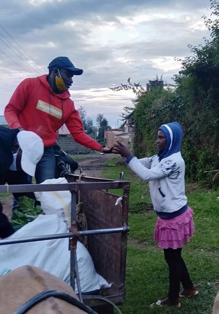 Simon on a cart handing food to a young girl