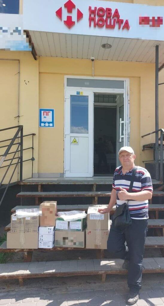 Good News: Ukrainian man standing near boxes of food and humanitarian supplies.