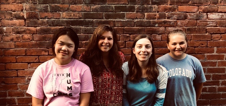 Four girls smile for a photo.