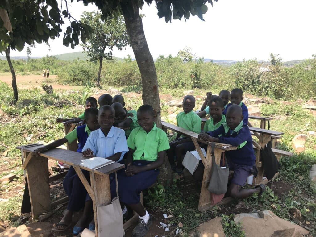 Children sit on benches outside