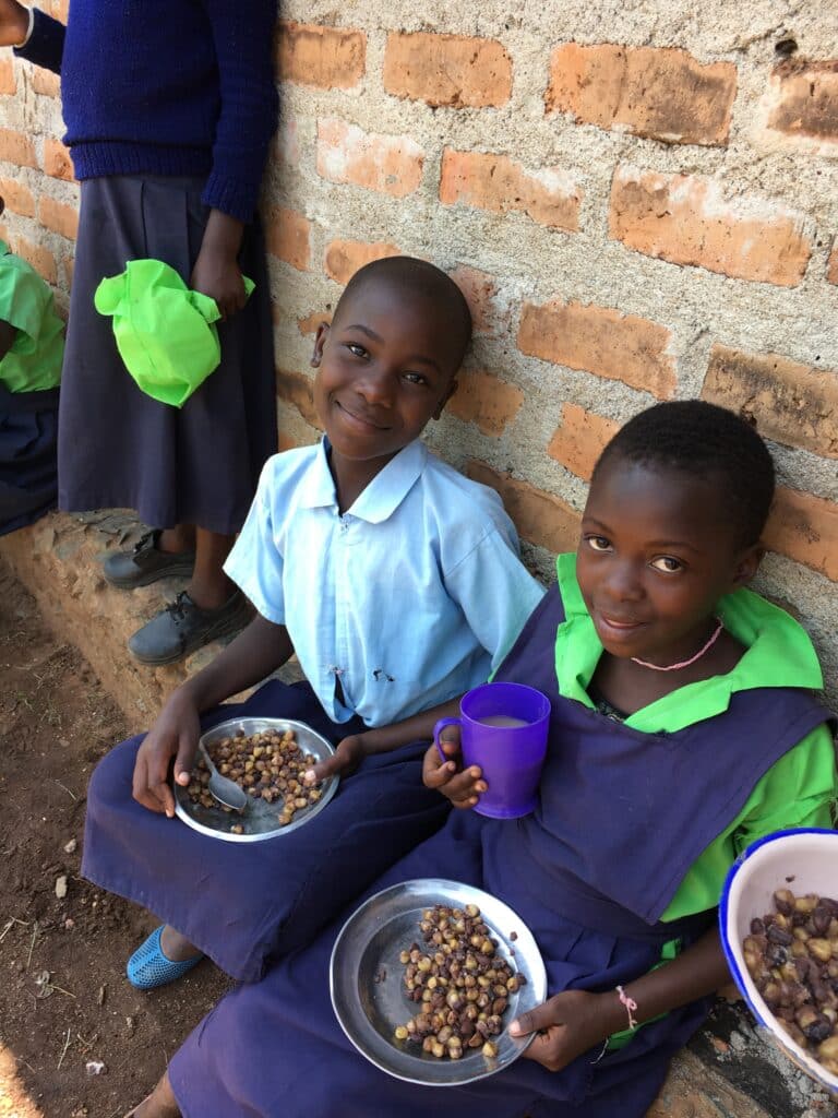 Two students eat lunch outside a brick building.