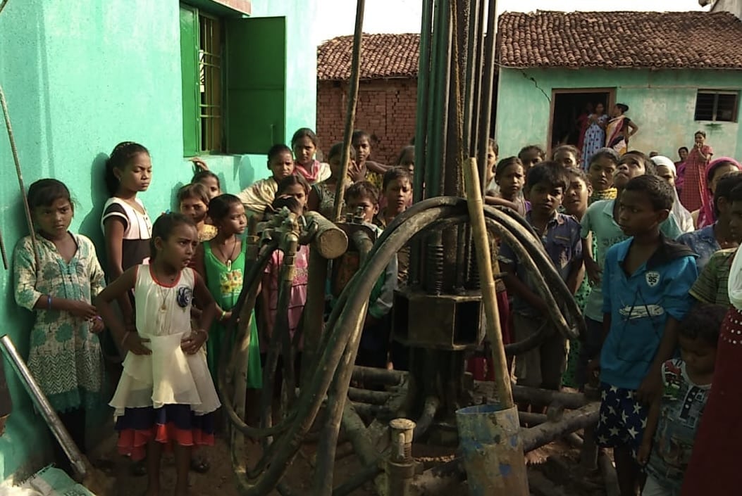 children in India Waiting by the drill and watching for water